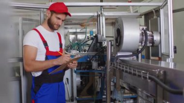 Üniformalı genç fabrika çalışanı su üretim fabrikasında panoya not alıyor.