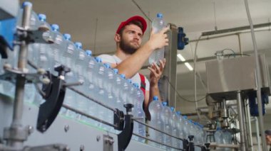 Su fabrikasında çalışan genç adam kaliteyi kontrol ediyor ve üretim sırasında teftiş yapıyor.