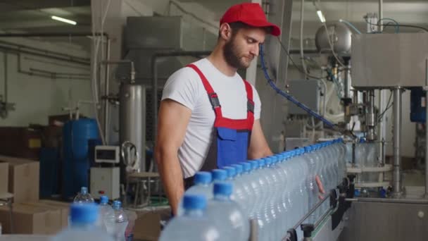 品質をチェックし、ライン生産で検査を行う水工場の若い男労働者 — ストック動画