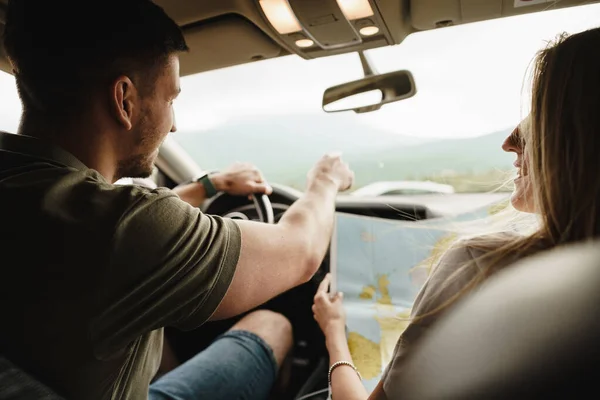 Молода любляча пара в дорожній поїздці, використовуючи карту всередині машини — стокове фото
