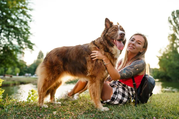 Jovem bela mulher acariciando seu cão bonito no parque — Fotografia de Stock