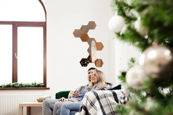 Dulce pareja abrazándose en el sofá en casa durante la Navidad — Foto de Stock
