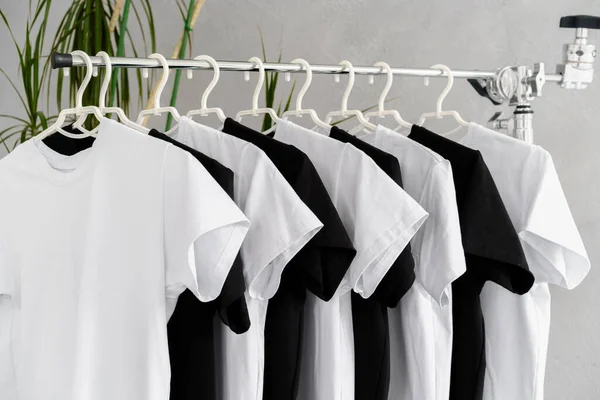 Rangée de t-shirts noirs et blancs suspendus sur rack — Photo