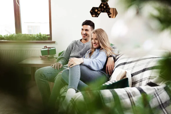 Dulce pareja abrazándose en el sofá en casa durante la Navidad — Foto de Stock