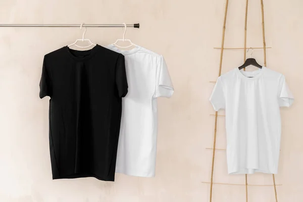 Weiße und schwarze T-Shirts auf Kleiderbügeln für die Designpräsentation — Stockfoto