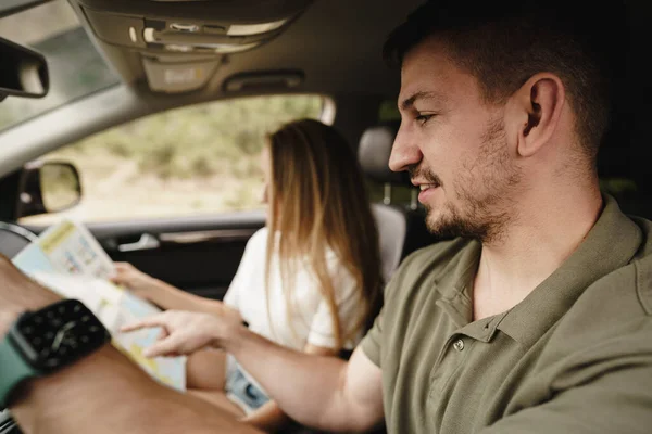 Молода любляча пара в дорожній поїздці, використовуючи карту всередині машини — стокове фото