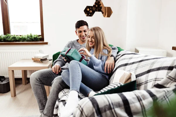 Dulce pareja abriendo regalos de Navidad en la sala de estar en casa — Foto de Stock