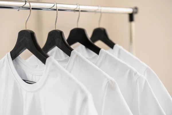 Fila de camisetas brancas em cabides em rack — Fotografia de Stock