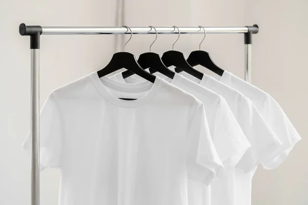 Fila de camisetas brancas em cabides em rack — Fotografia de Stock
