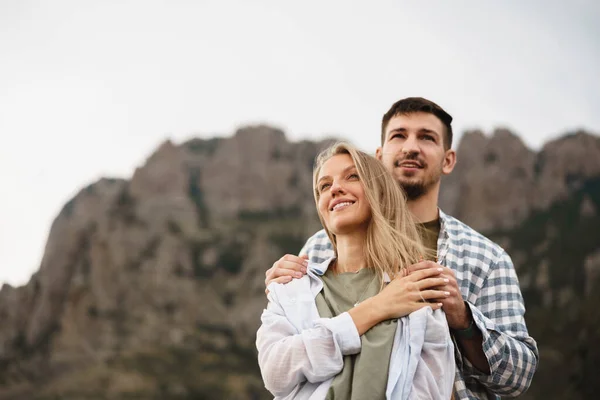 Feliz pareja cariñosa senderismo y abrazos en las montañas — Foto de Stock