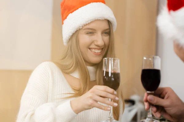 Young couple in Santa hats drinking wine and celebrating Christmas Royalty Free Stock Images