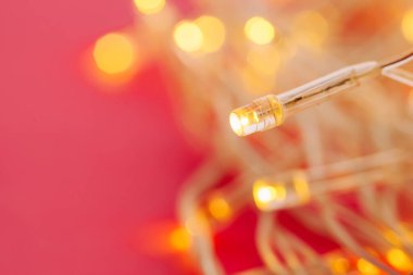 Parlak pembe arka planda aydınlatılmış çelenk ışıkları