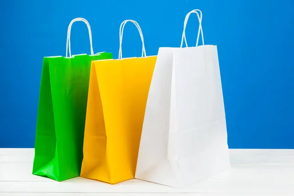 Sacos de compras de papel com espaço de cópia no fundo azul — Fotografia de Stock