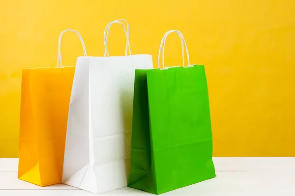 Sacos de compras de papel no fundo amarelo brilhante — Fotografia de Stock