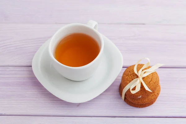 Cup of tea with cookies over lilac wooden background — Stock Photo, Image