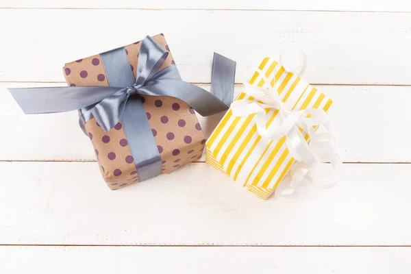Tied bows gift boxes on white wooden background, top view — Stock Photo, Image