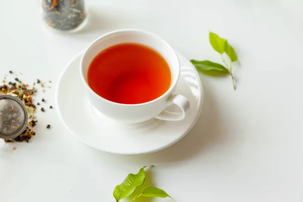 Tasse de thé noir chaud sur table blanche avec pot de thé sec — Photo