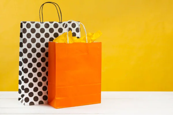 Arranjo de sacos de compras no fundo amarelo brilhante — Fotografia de Stock