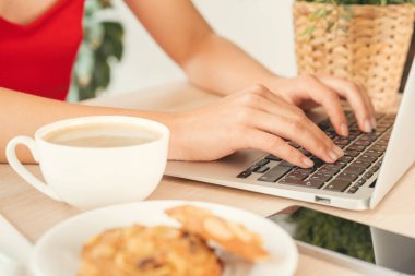 Ofiste çalışan, bilgisayar kullanan, masa başında oturan genç bir kadın.