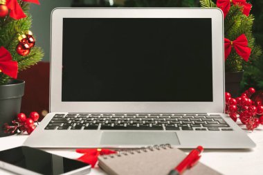 Masadaki dizüstü bilgisayarı ve defteri noel dekoruyla aç