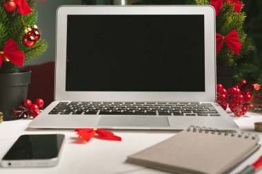 Masadaki dizüstü bilgisayarı ve defteri noel dekoruyla aç