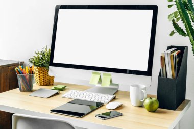 Ofis masasında malzemelerle birlikte beyaz ekranlı bilgisayar monitörü