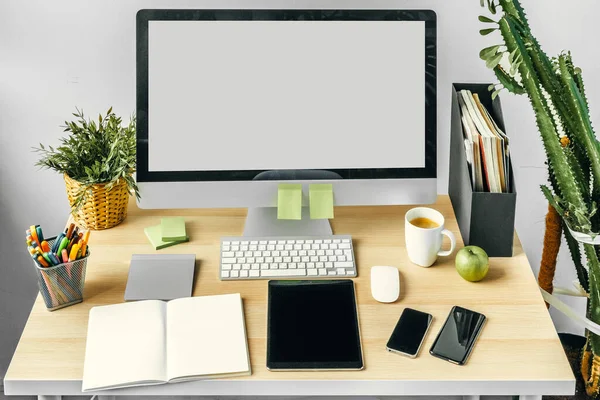 Monitor de computadora con pantalla blanca maqueta en la mesa de la oficina con suministros —  Fotos de Stock