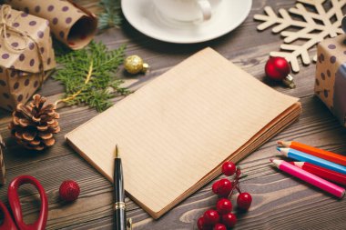 Yılbaşı tebrik kartları yazıyorum. Süslü ahşap masadaki kalemle birlikte defteri aç