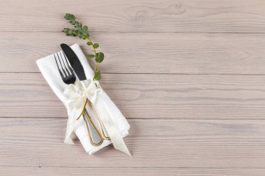Ahşap bir masaya peçeteye sarılı çatal bıçak takımı.