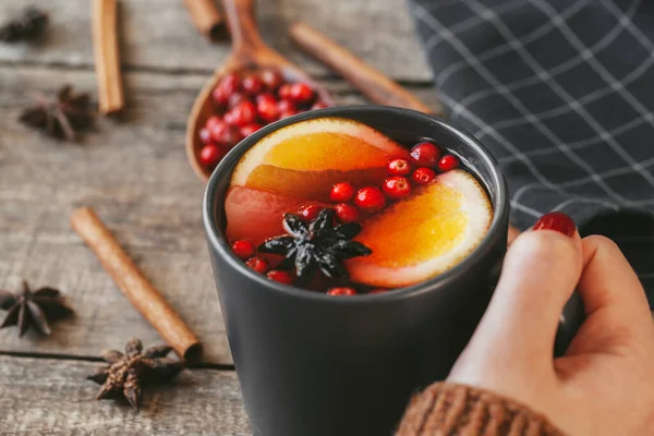 Womans hands in warm sweater holding a cup of mulled wine — Stock Photo, Image