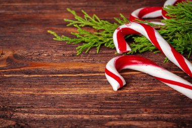 Noel arkaplanı süslenmiş ahşap masadaki baston şekerlerle dolu.