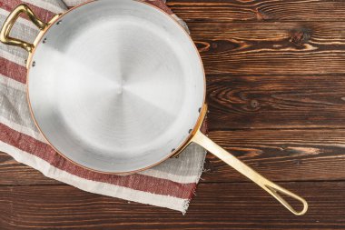 Tahta masa örtüsü olan bakır tencere.