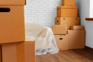 Bir odada paketlenmiş kanepe ve karton kutular. Taşınma konsepti