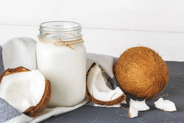 Kokosnuss und Glas Kokosmilch auf Holzgrund — Stockfoto