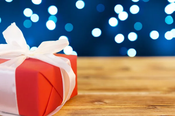 Невеликі різдвяні подарункові коробки на дерев'яному столі на фоні вогнів боке — стокове фото