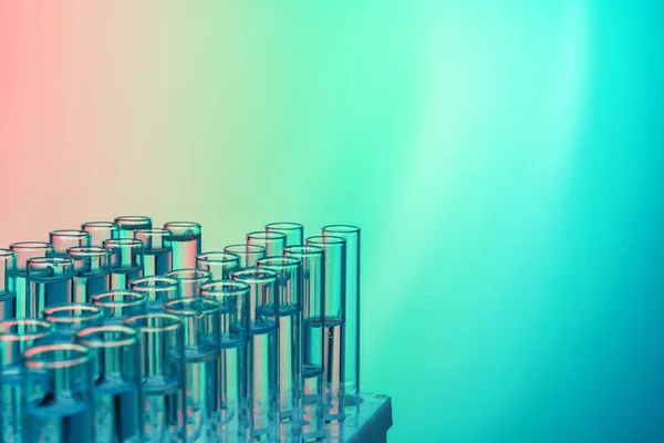 Rij van reageerbuizen met vloeistoffen op een blauwe en groene achtergrond — Stockfoto
