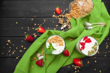 Siyah ahşap arka plan üzerinde yoğurt ve çilek ile yulaf ezmesi. Üst te. Sağlıklı kahvaltı.