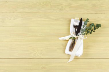 Ahşap bir masaya peçeteye sarılı çatal bıçak takımı.