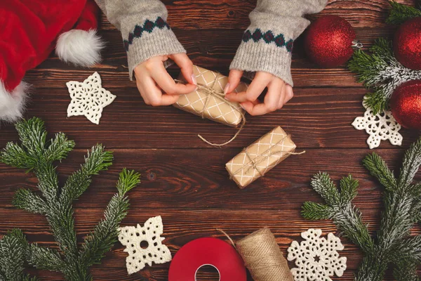 手穿毛衣，拿着圣诞礼物放在木制桌子上 — 图库照片