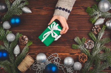 Noel süslemeleri ahşap masada, süslü hediyeler de kadınların elinde.