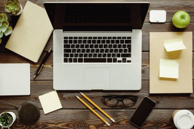 Dizüstü bilgisayar, sarf malzemeleri ve yeşil elma ile Ofis masası, üst görünüm