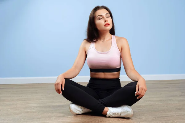 Fit woman in sportswear sitting on the floor in a gym — Stock Photo, Image