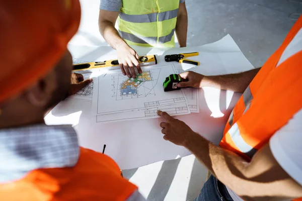 Närbild av tre ingenjörer tittar på ritning på byggarbetsplatsen — Stockfoto