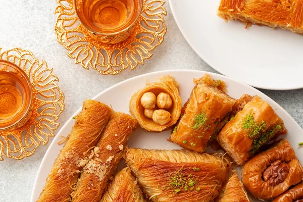 Various Turkish sweets and cup of tea on white textured background — Stock Photo, Image