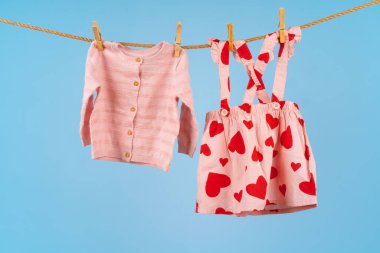 Bebek kıyafetleri mavi arka planda çamaşır ipine takılmış.