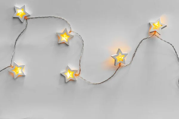 Guirnalda iluminada en forma de estrella sobre fondo gris claro —  Fotos de Stock