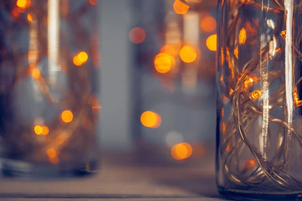 Licht bloemenslinger in een glazen fles op een donkere achtergrond — Stockfoto