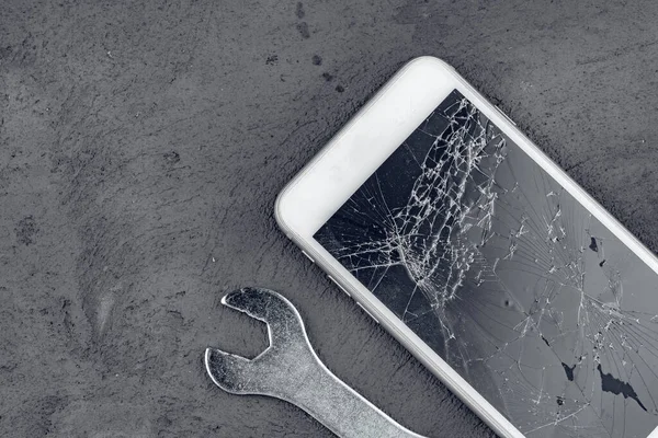 Gri arkaplanda tamir araçları ile çökmüş akıllı telefon