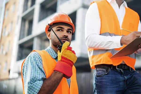 Jovem trabalhador da construção em uniforme usando walkie talkie no local — Fotografia de Stock