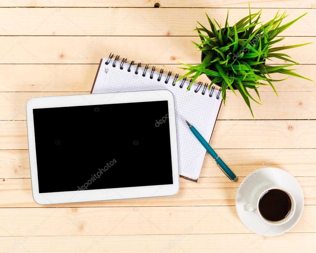 Tablet, notepad, computer and coffee cup on office wooden table